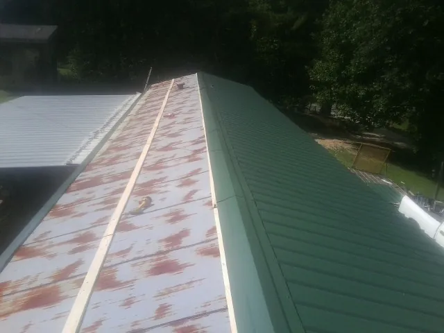 Old rusted panels beside newly installed green metal roofing — Wind Damage Roof Repair by Roofing Brothers in Chestertown