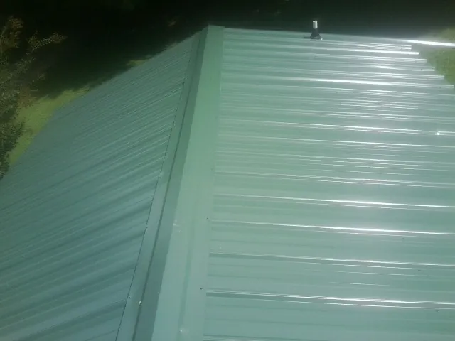New green metal panels meeting at the ridge of a roof — Flat Roof Repair work by our crew in Chestertown