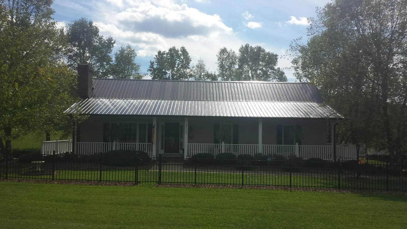 Gray metal roof on a brick ranch with a full width front porch — Gutter Guard Installation work by our crew in Chestertown