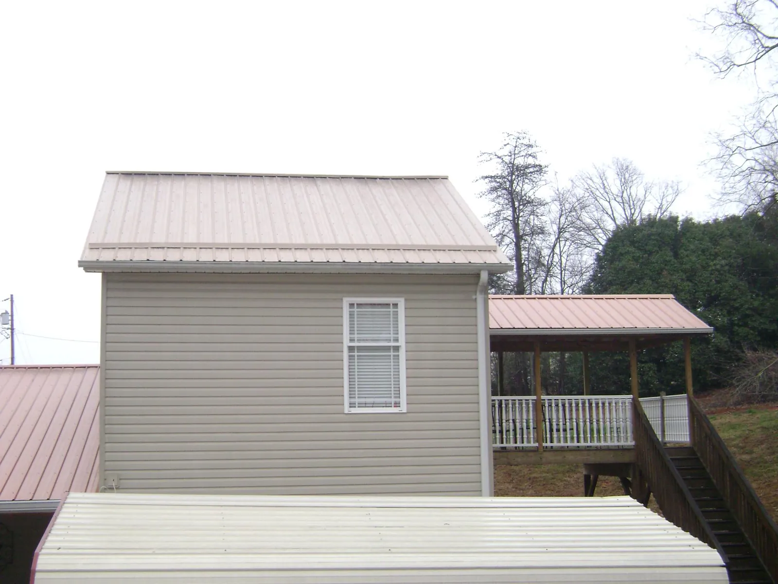 Tan metal roofs on a two story addition and attached porch, from a Roof Replacement job in Chestertown