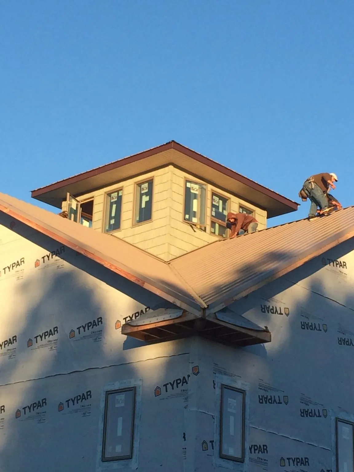 Roofers working around a rooftop cupola on a new metal roof at sunset — Roof Waterproofing in Chestertown by Roofing Brothers